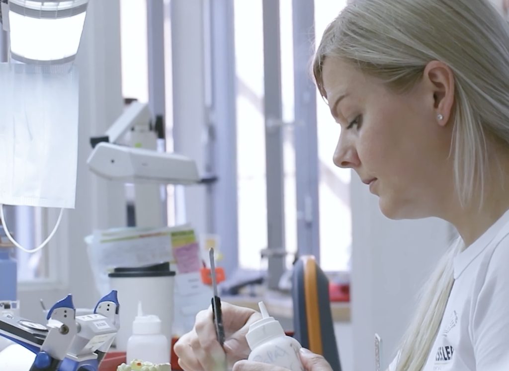 Zahntechnikerin bei der Verblendarbeit am Arbeitsplatz